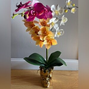 Faux orchid arrangement in gold-colored skull votive